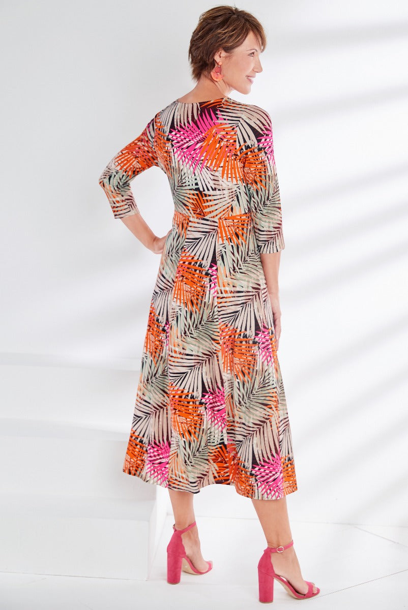 Lily Ella Collection tropical print midi dress in orange, pink, and white, three-quarter sleeves with tie waist, paired with pink heels, fashion-forward women's clothing.