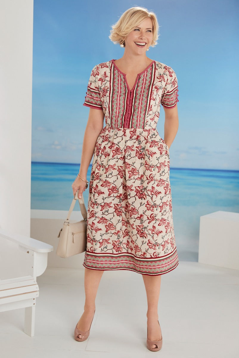 Lily Ella Collection floral mid-length dress in cream with red floral pattern and striped accents, styled with beige heels and a matching handbag for a summer chic look.