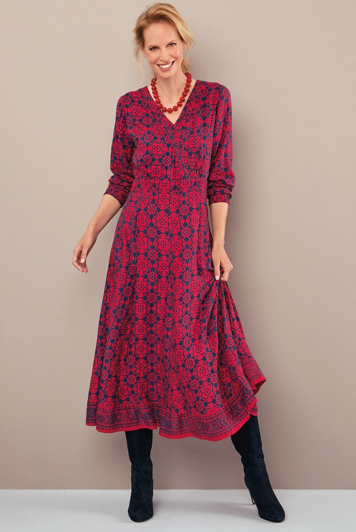 Lily Ella Collection red patterned midi dress with three-quarter sleeves, V-neckline paired with black knee-high boots and chunky red necklace, stylish women's autumn fashion.