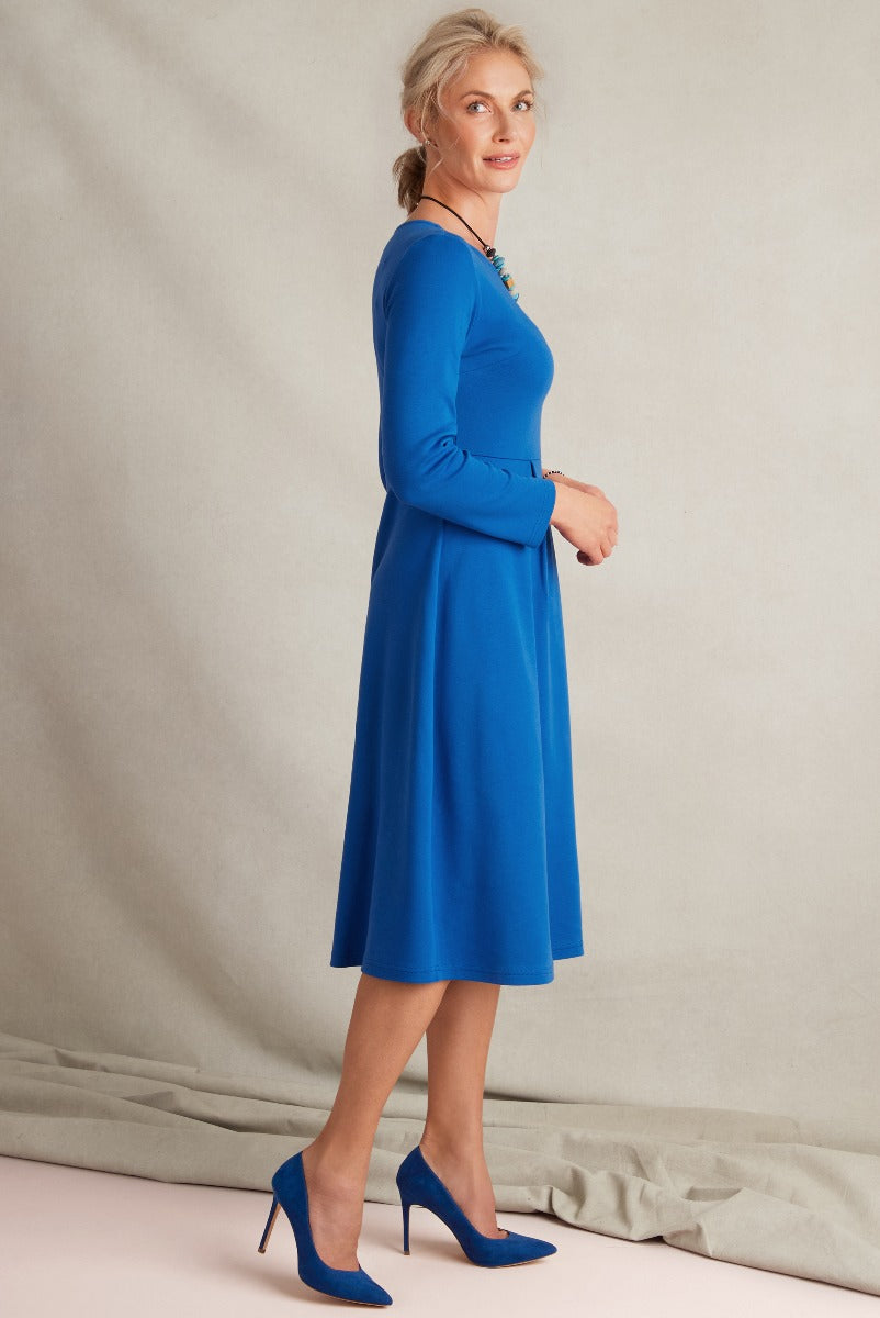 Lily Ella Collection elegant royal blue midi dress with fitted long sleeves and matching blue high heels, featuring a sophisticated female model in a contemporary fashion look.