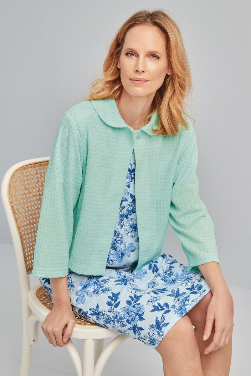Lily Ella Collection mint green textured jacket and blue floral print dress, stylish women's wear fashion, model seated on white wicker chair