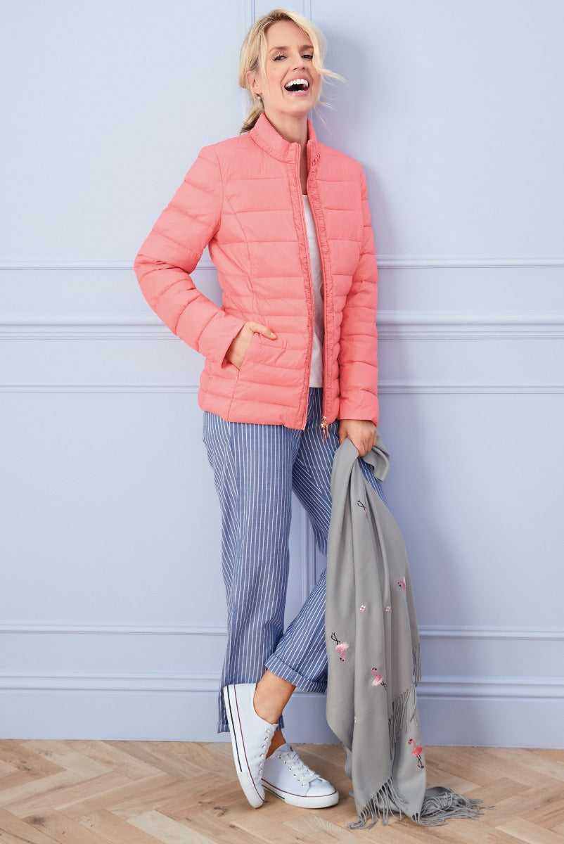 Lily Ella Collection vibrant coral pink quilted jacket paired with striped trousers and floral grey scarf for women’s spring fashion essentials.