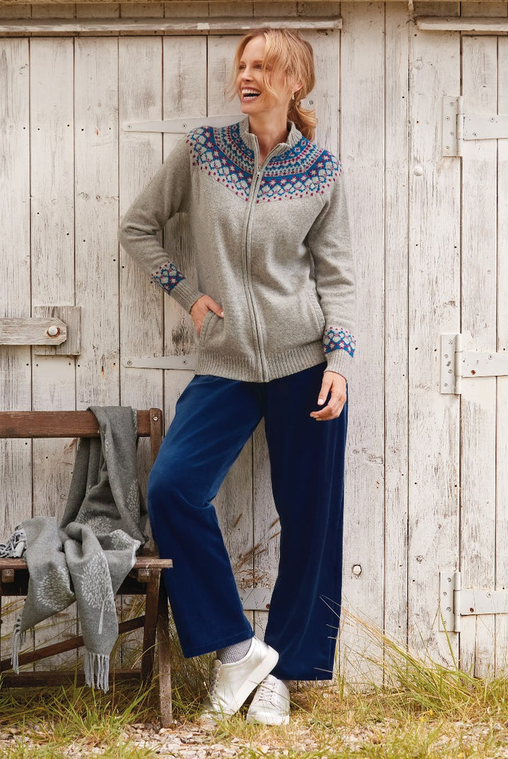 Lily Ella Collection grey zip-up cardigan with blue and red pattern details paired with navy blue trousers, outdoor rustic setting.