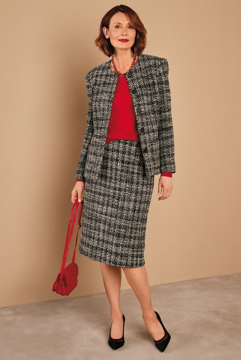 Lily Ella Collection stylish woman wearing elegant houndstooth black and white wool blend blazer and skirt set with a vibrant red top and matching bead necklace, complemented by a red leather shoulder bag and black heels, perfect for business or sophisticated casual wear