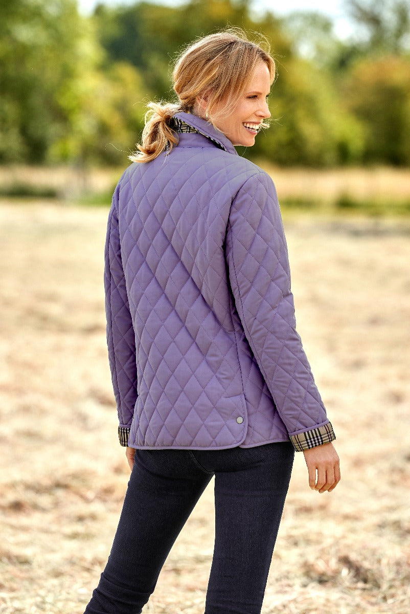 Lily Ella Collection women's purple quilted jacket with patterned cuffs and button details styled with dark jeans for a casual autumn look