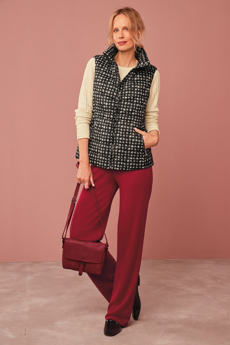 Lily Ella Collection stylish quilted black and white gilet over a classic cream sweater paired with elegant wine-red trousers, accessorized with a matching crossbody bag and black loafers, perfect for a sophisticated casual look.