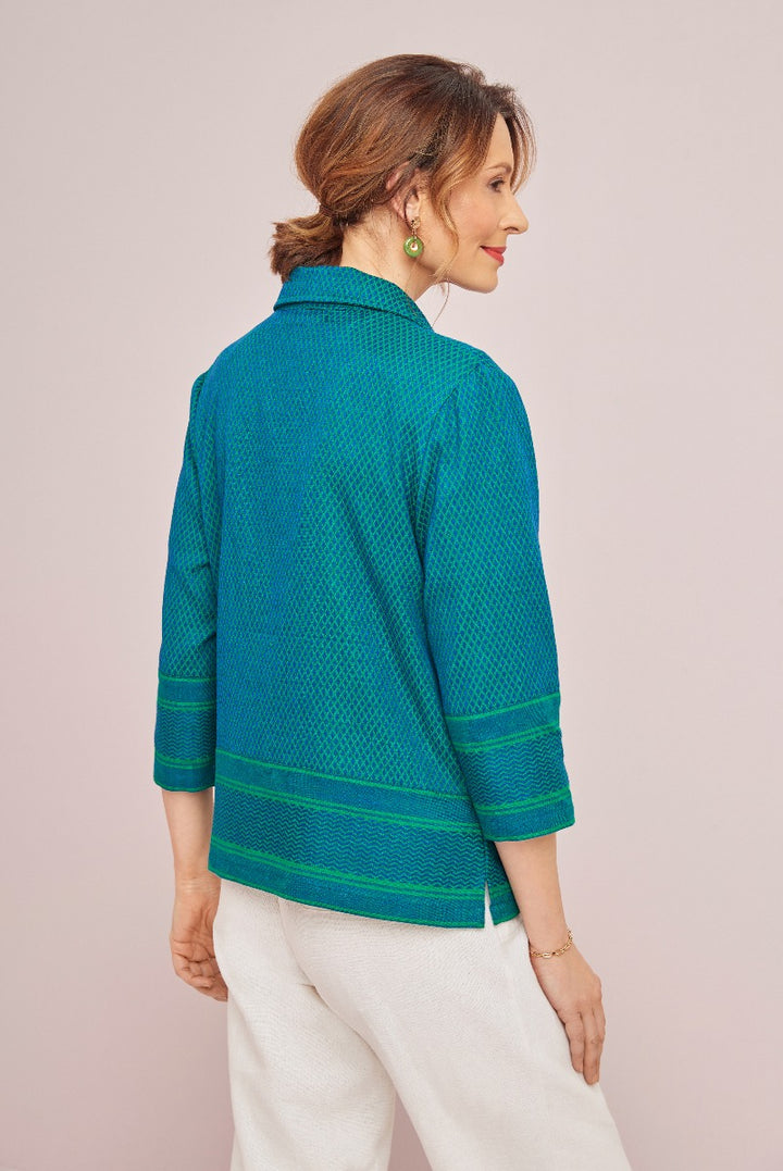 Lily Ella Collection teal textured jacket with green trim, stylish elegant outerwear, woman modeling modern casual spring attire, rear view showing design details on pastel background.