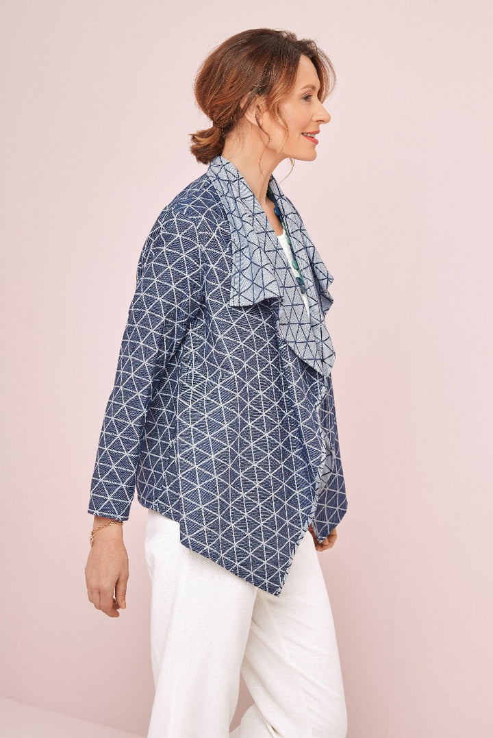 Lily Ella Collection navy blue geometric patterned jacket styled with white trousers, elegant women's casual fashion, side view.