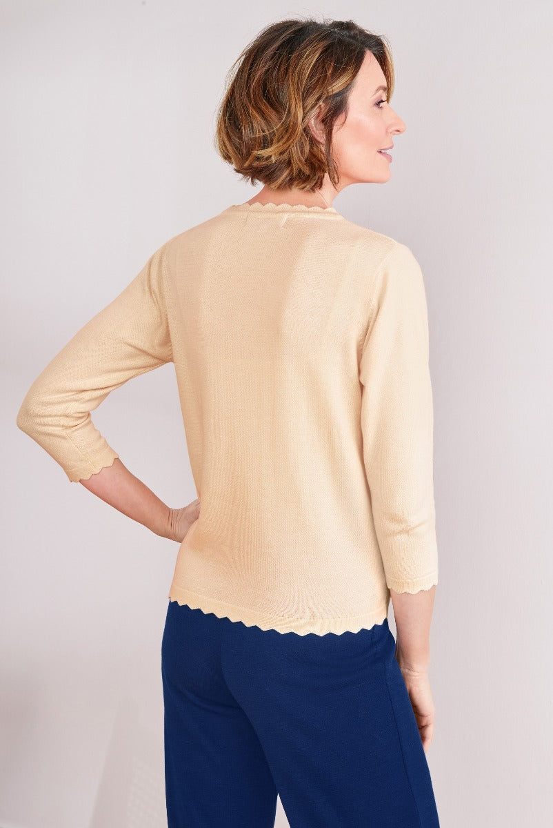 Lily Ella Collection classic cream knit sweater, women's elegant 3/4 sleeve pullover, scalloped hem detailing, paired with navy trousers.