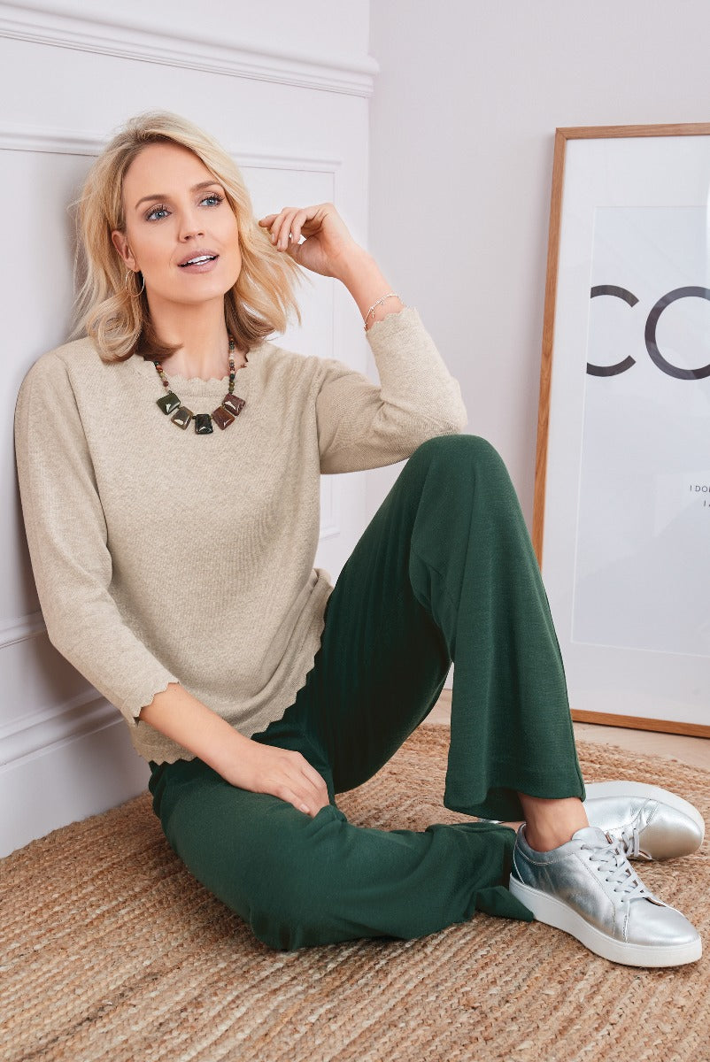 Lily Ella Collection elegant beige sweater and forest green trousers outfit modeled with statement necklace and casual metallic sneakers