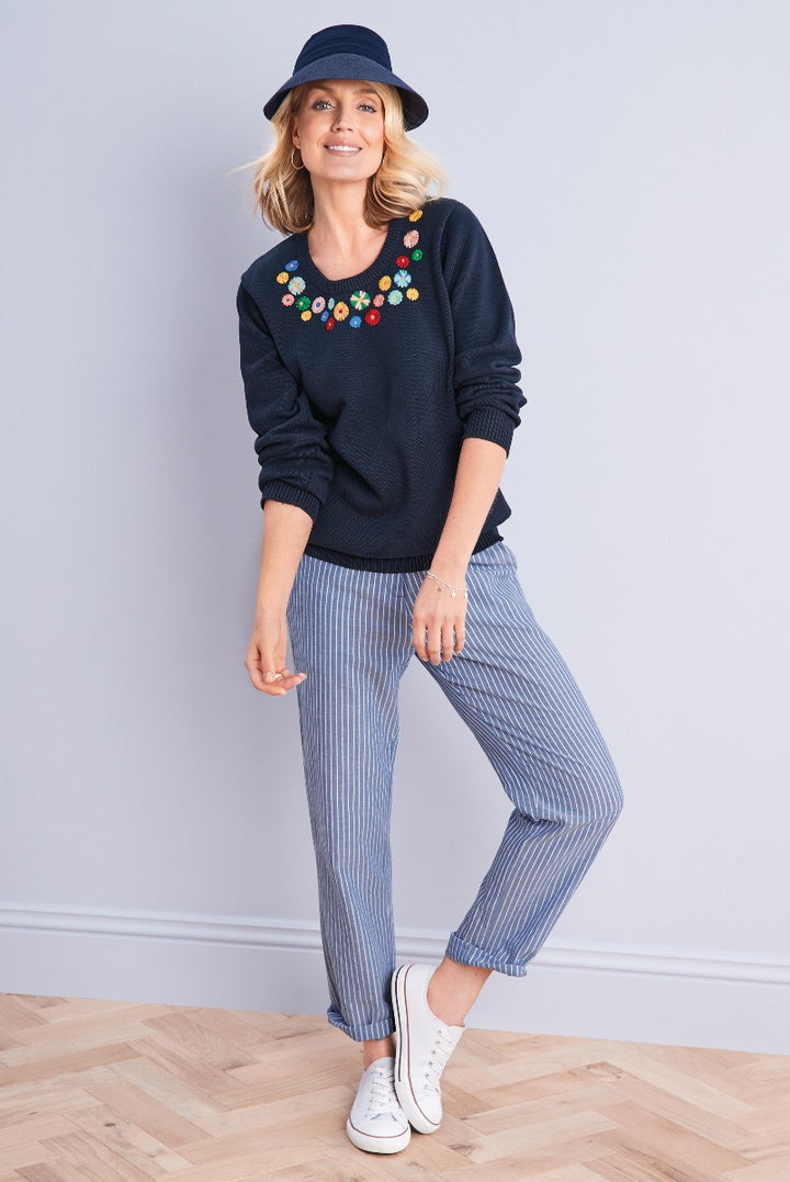 Lily Ella Collection navy blue jumper with colorful floral embroidery paired with blue and white striped trousers and white sneakers, featuring casual yet stylish women's apparel.