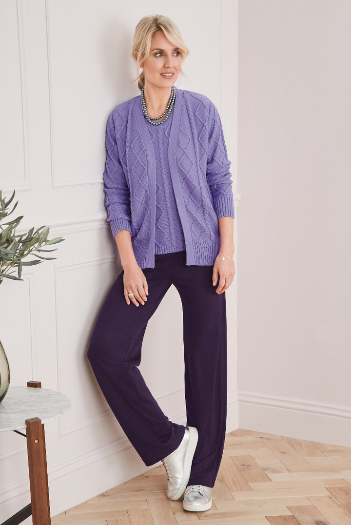 Lily Ella Collection lavender cable knit cardigan and purple trousers on model with silver sneakers, stylish mature women's fashion, elegant casual outfit
