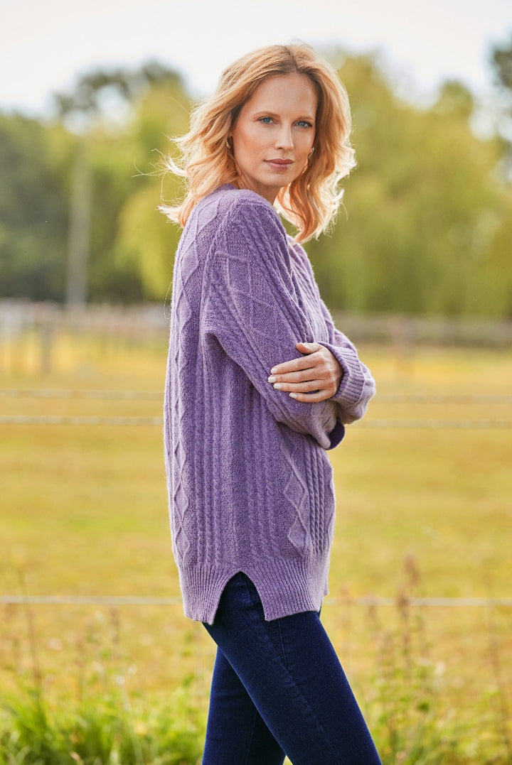Lily Ella Collection purple cable knit sweater, cozy casual style, woman modeling in outdoor setting, soft-focus nature background