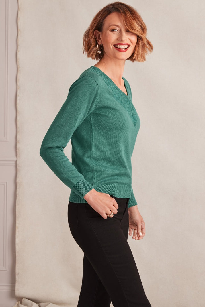 Lily Ella Collection emerald green textured knit jumper, stylish women's v-neck sweater, elegant casual fall clothing, model wearing designer top and black trousers.