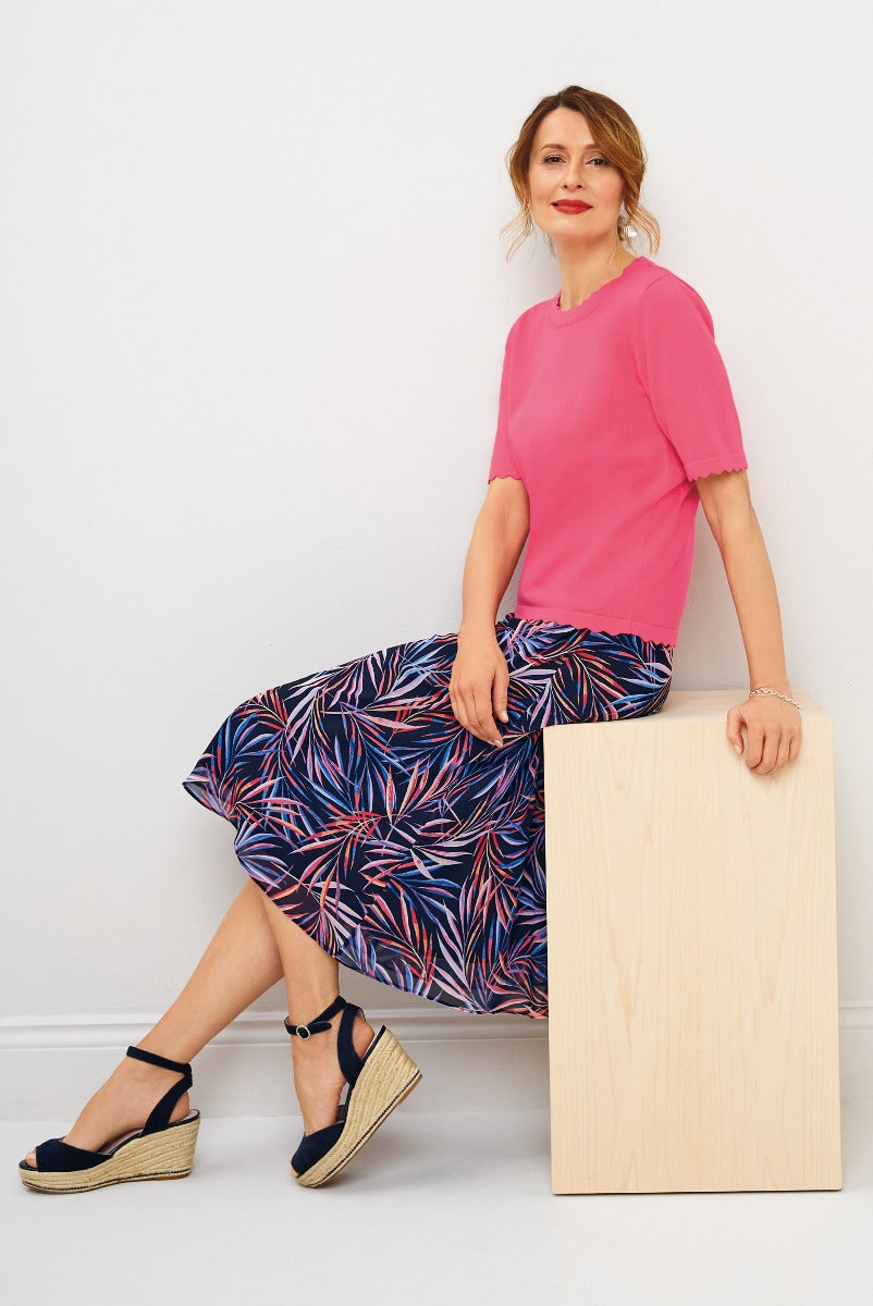 Lily Ella Collection chic pink top and patterned navy skirt with tropical print, styled with black wedge sandals for a smart casual look.