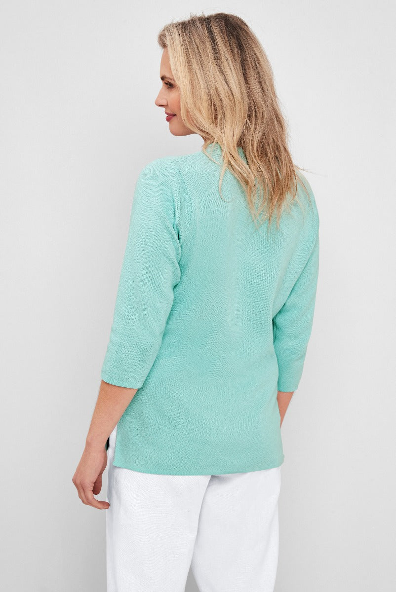 Lily Ella Collection casual mint green knit jumper with elegant pattern detail and three-quarter sleeves, paired with white trousers for a fresh spring outfit.