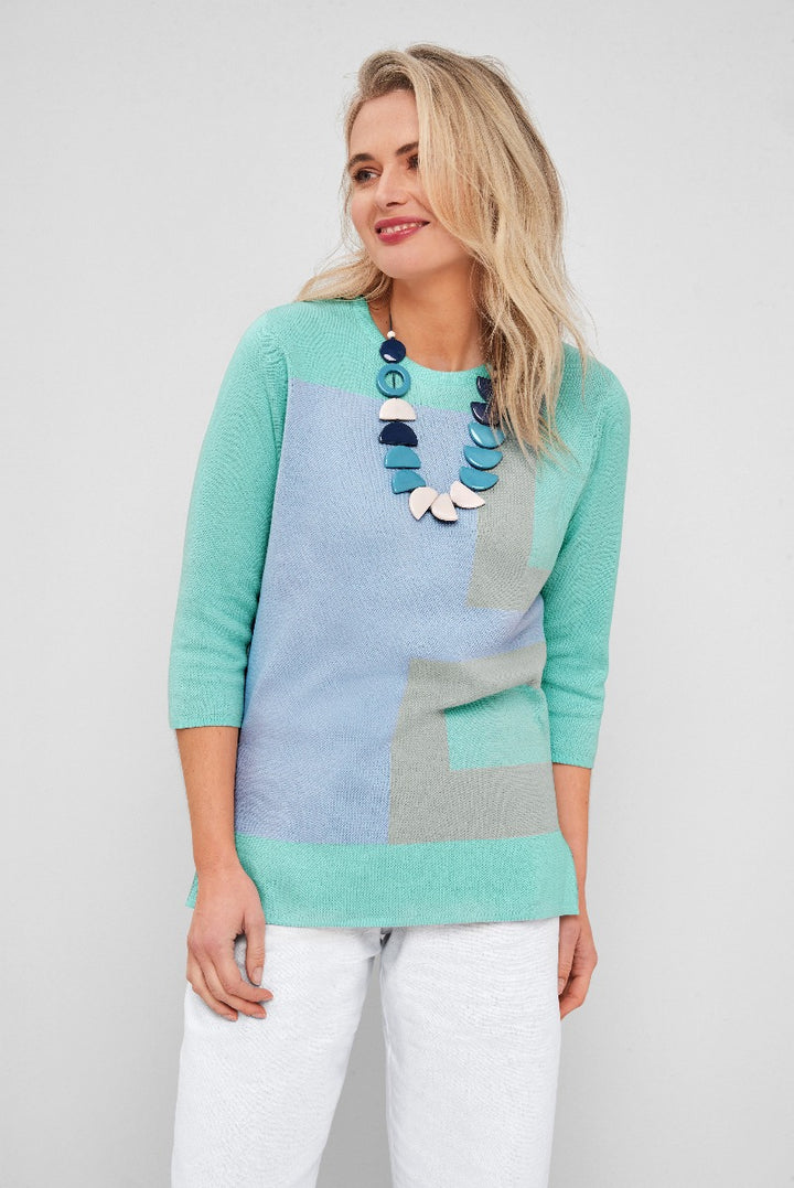 Lily Ella Collection women's pastel colorblock jumper in aqua blue, mint green, and grey, stylish three-quarter sleeve knitwear with front pocket detail, paired with elegant statement necklace and white pants.