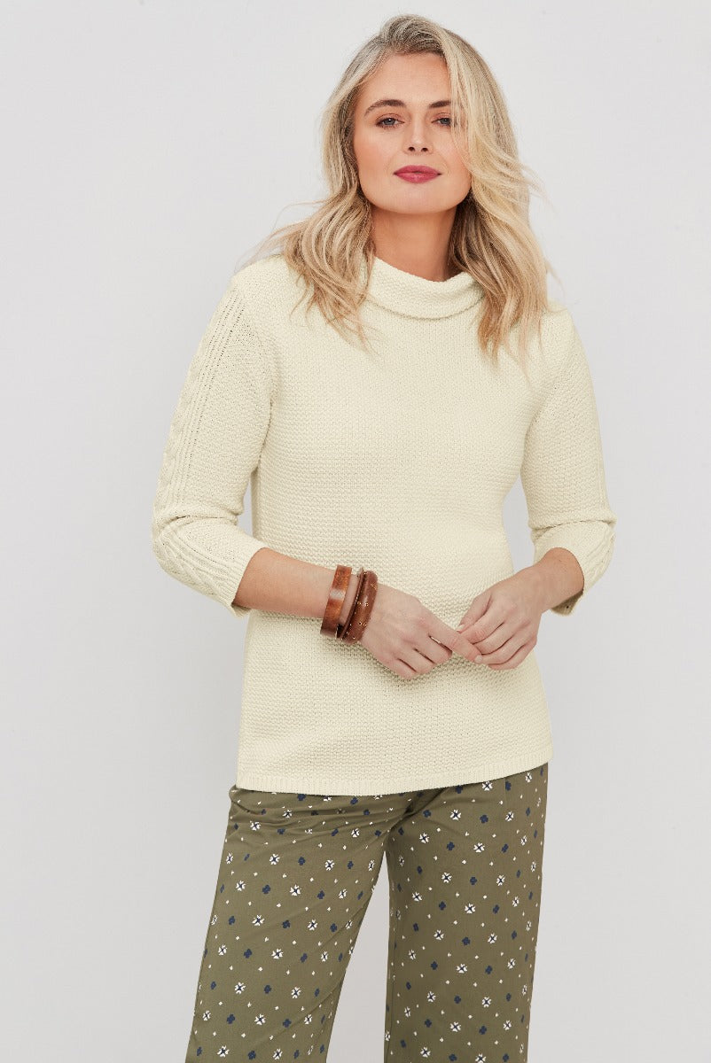 Lily Ella Collection cream turtleneck sweater, stylish casual knitwear, paired with patterned olive trousers and accessories, modern women’s fashion.