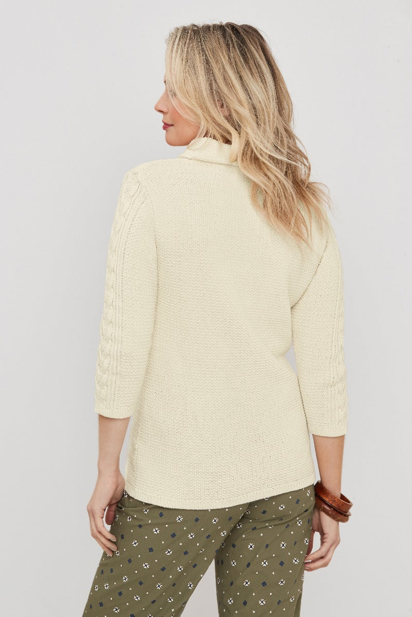 Lily Ella Collection ivory cable knit sweater with ribbed detailing on sleeves and relaxed fit, paired with patterned olive trousers, showcasing casual elegance for women's fashion.