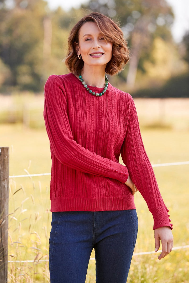 Lily Ella Collection stylish red ribbed sweater with button cuff details worn by smiling model in outdoor setting