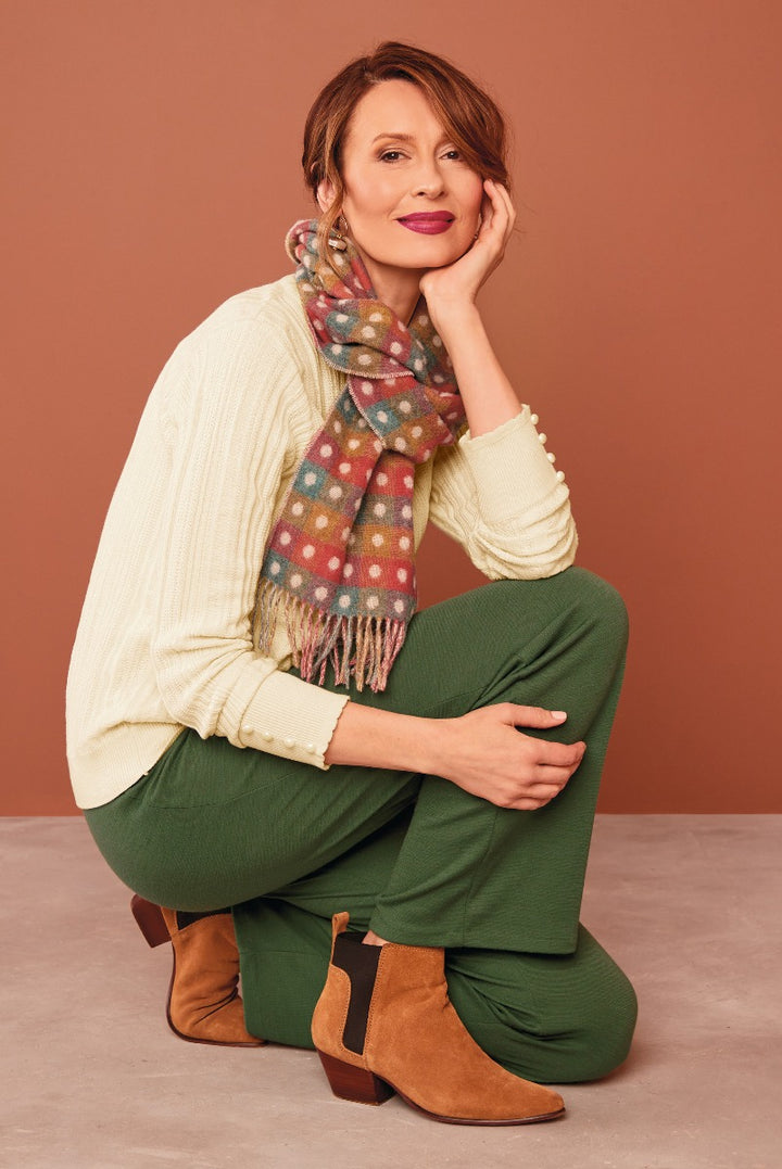 Lily Ella Collection stylish cozy outfit with cream sweater, olive green trousers, multicolor polka dot scarf, and brown ankle boots, elegant casual women's wear.