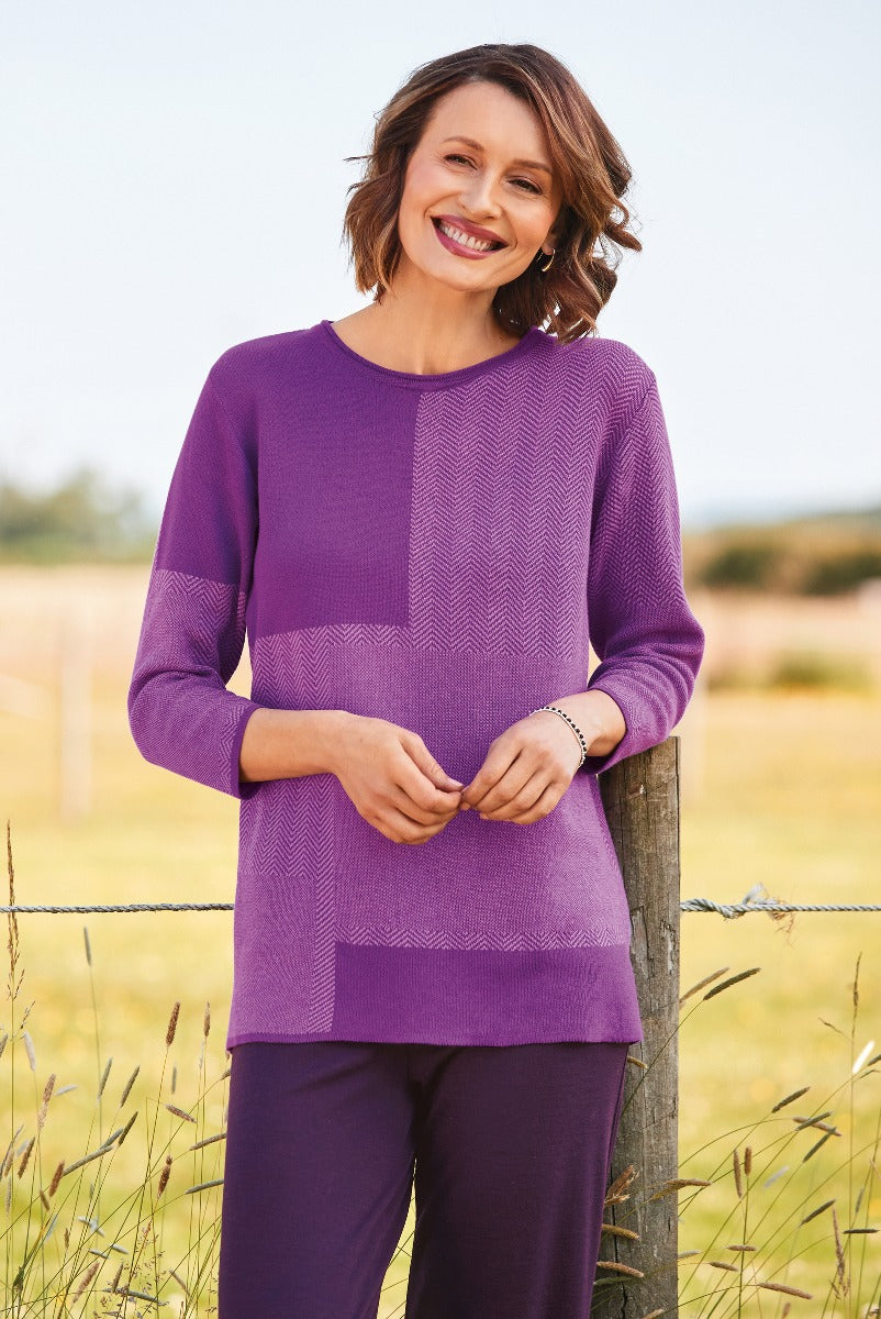 Lily Ella Collection purple knitwear, smiling woman wearing textured plum jumper, stylish chevron pattern, casual autumn fashion, comfortable chic clothing, outdoor photoshoot.