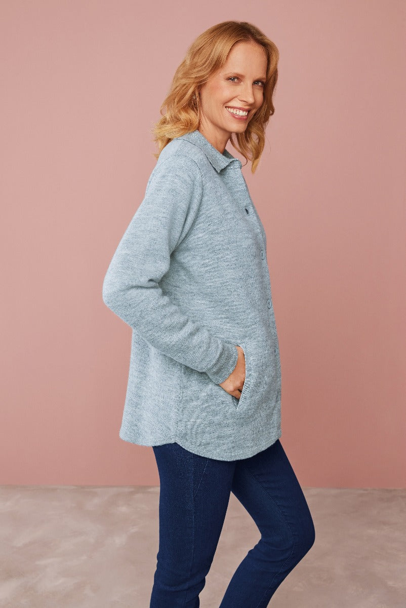 Lily Ella Collection light blue button-up cozy cardigan with a smiling woman, casual chic style, paired with dark blue jeans against a soft pink background.