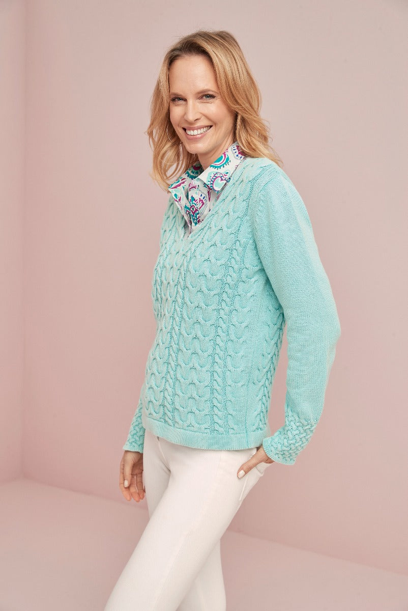 Lily Ella Collection aqua blue cable knit sweater with floral blouse and white trousers, stylish women's casual wear, elegant spring outfit idea.
