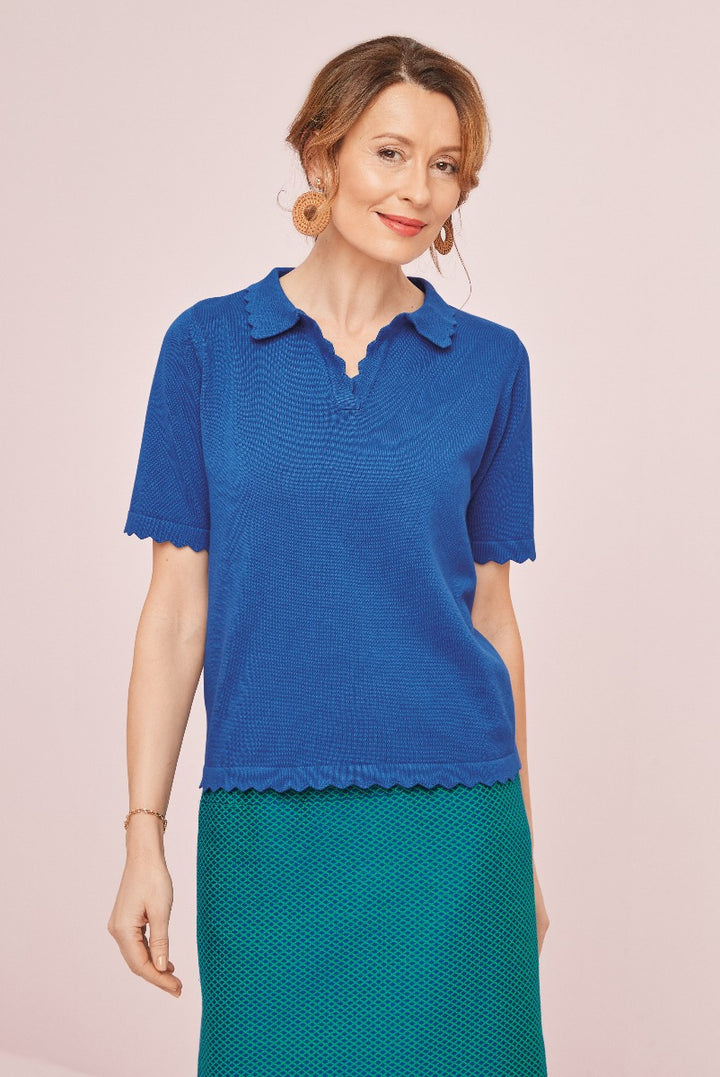 Lily Ella Collection royal blue knitted top with scallop trim on collar and sleeves, stylish mature woman modeling, elegant casual wear, paired with green skirt.
