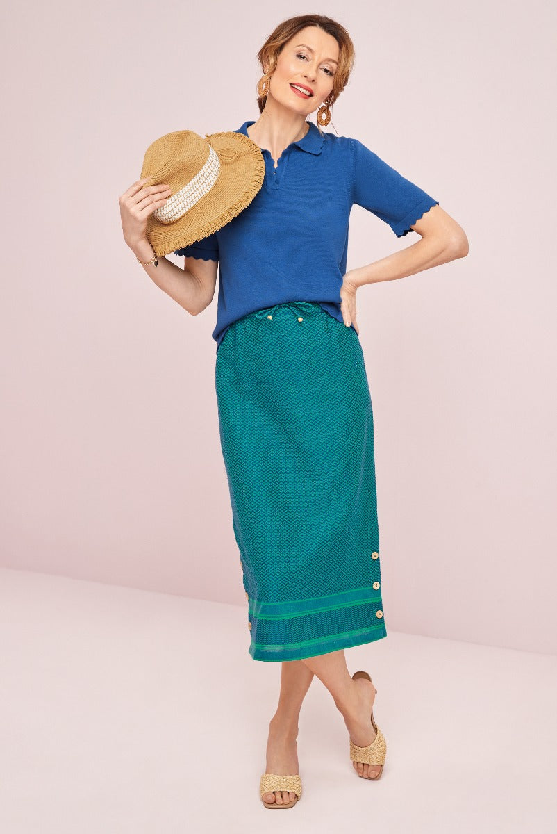 Lily Ella Collection elegant blue polo shirt and green button-detail skirt with straw hat and wedge sandals, stylish mature women's fashion