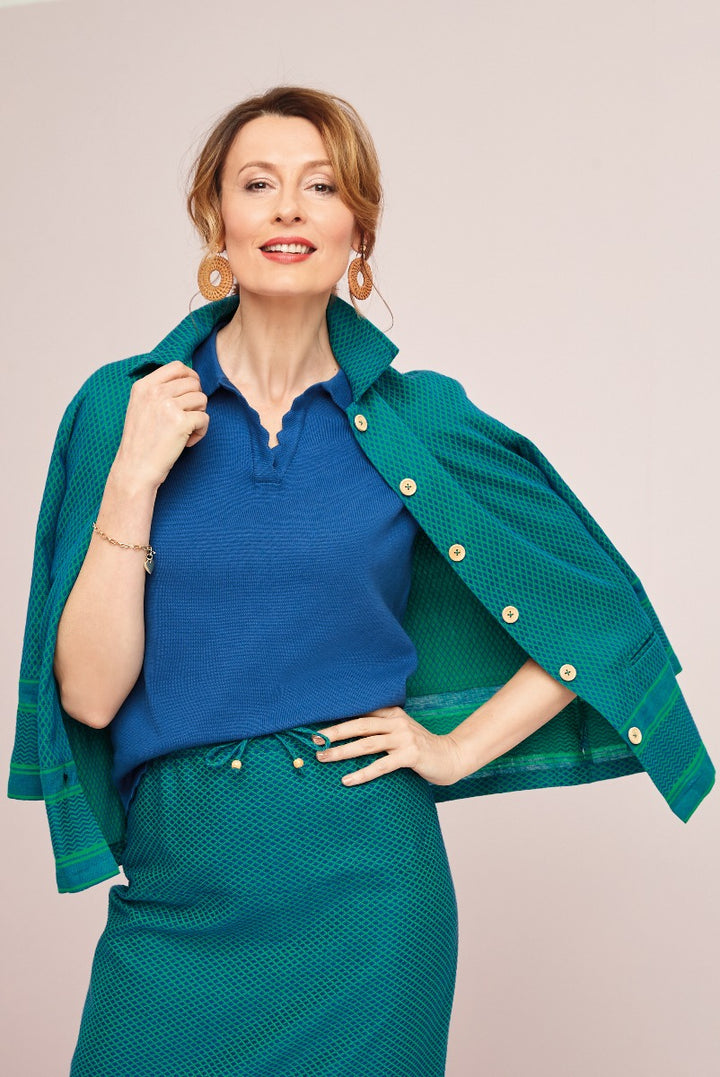 Lily Ella Collection elegant royal blue knit top and emerald green patterned skirt with coordinating green jacket, stylish outfit for women, fashion model posing with gold statement earrings
