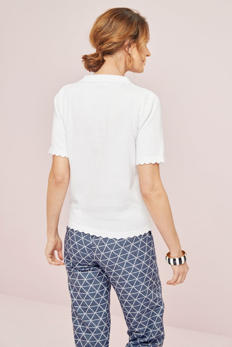 Lily Ella Collection's white scallop-edged t-shirt paired with patterned navy trousers, stylish women's casual wear, elegant geometric print pants, versatile day-to-evening outfit idea