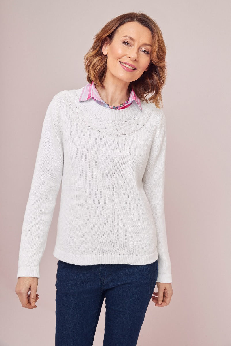Lily Ella Collection white classic knit sweater with detailed neckline, layered with pink striped collar shirt, paired with dark denim jeans, elegant casual women's fashion.