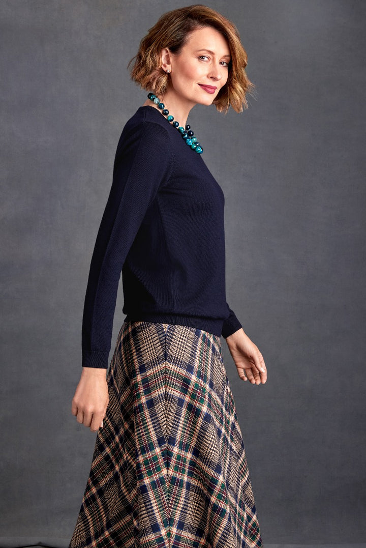 Lily Ella Collection elegant navy blue sweater with statement turquoise necklace and classic plaid skirt, stylish women's autumn outfit.