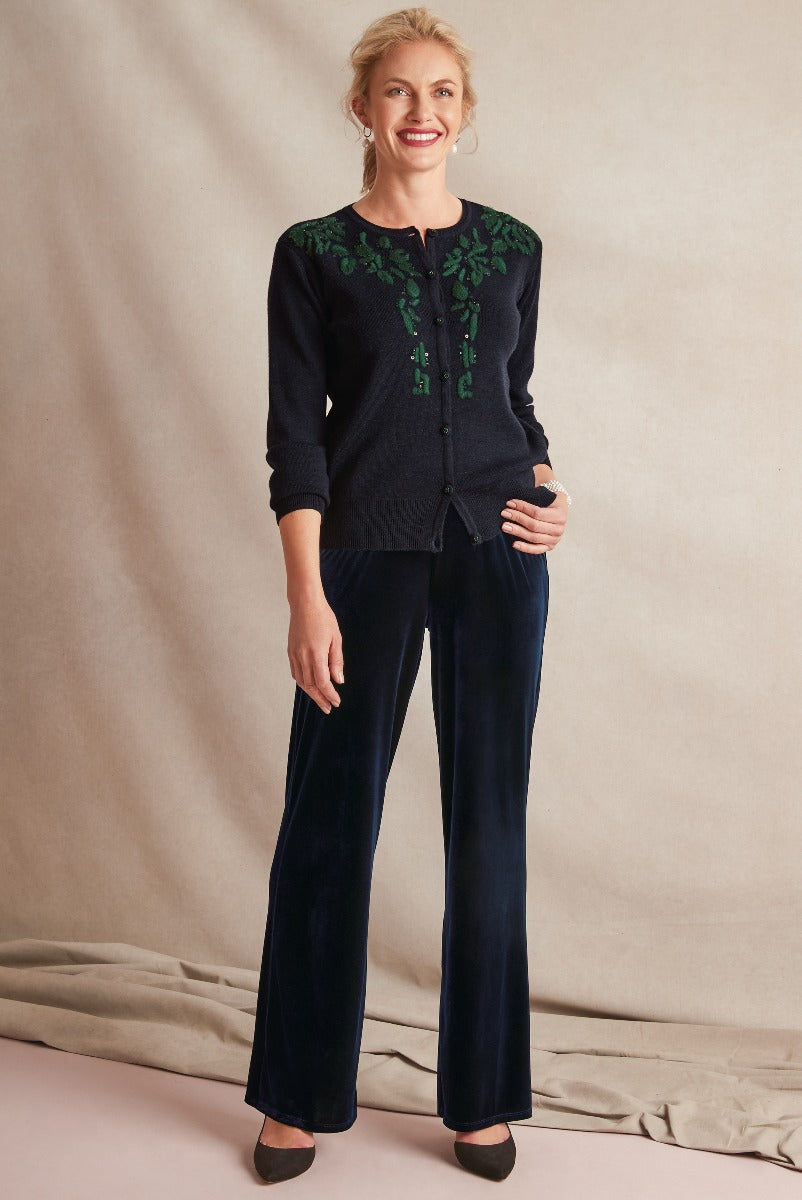 Lily Ella Collection elegant woman modeling black cardigan with green embroidery and navy velvet trousers, sophisticated casual style, fashionable outfit idea