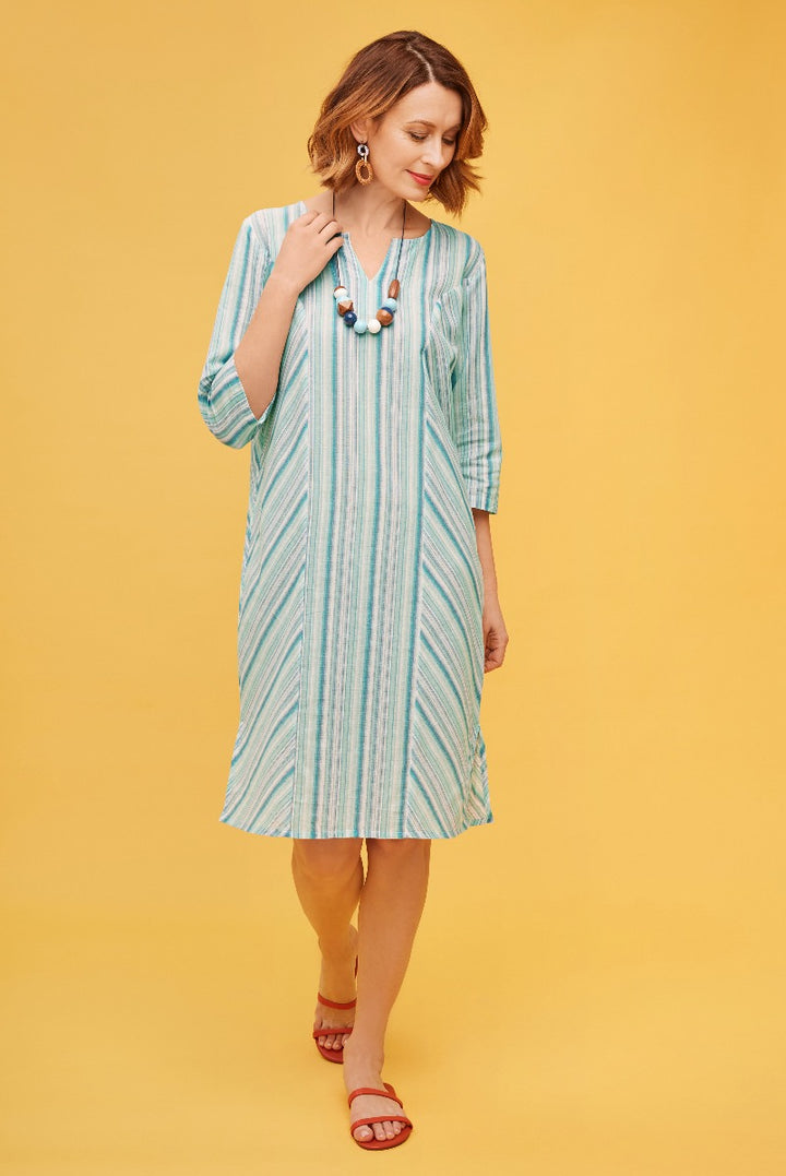 Lily Ella Collection aqua blue striped midi dress with 3/4 sleeves and mandarin collar, accessorized with a statement necklace and red sandals on a yellow background.