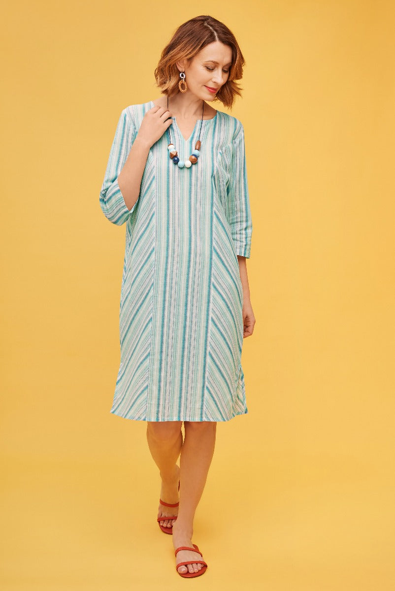 Lily Ella Collection aqua and white striped midi dress with three-quarter sleeves, tunic neckline, styled with red sandals and statement necklace on yellow background.
