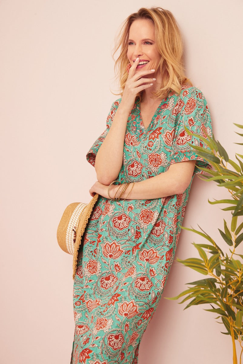 Lily Ella Collection teal floral print midi dress, stylish women's summer fashion, model holding straw hat beside tropical plant