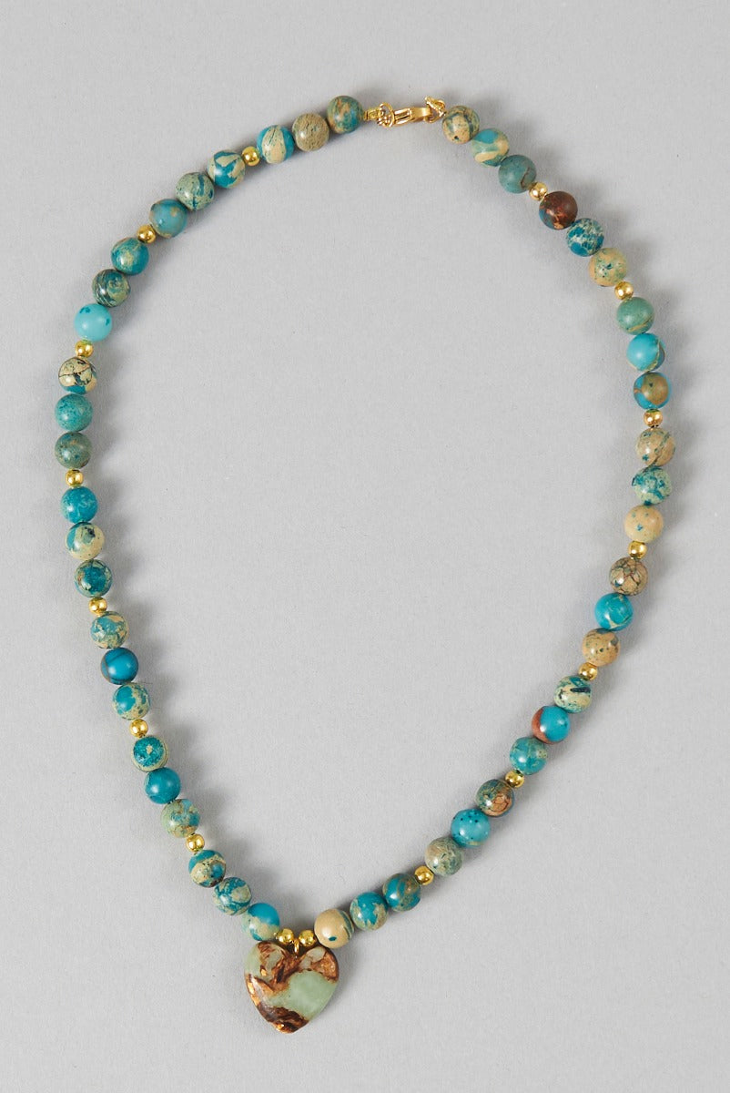 Lily Ella Collection turquoise beaded necklace with heart-shaped pendant and gold accents on a neutral background.
