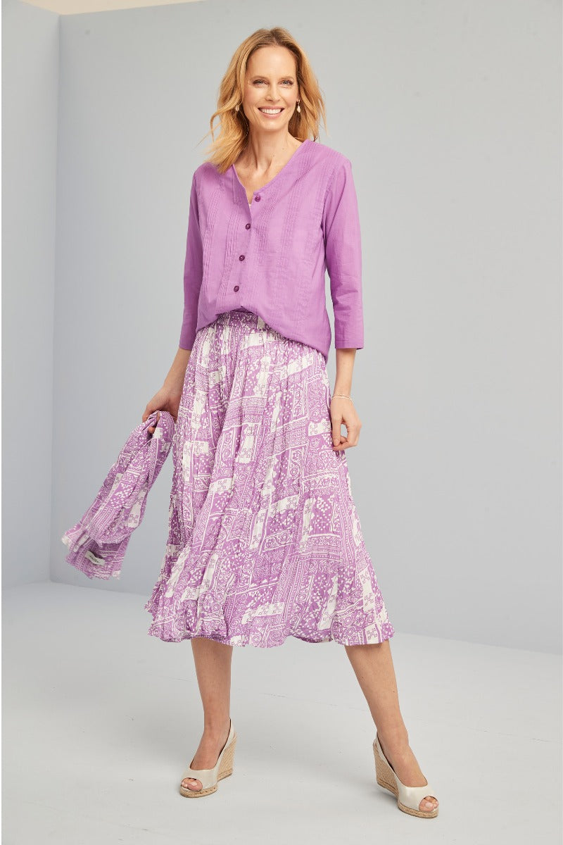 Lily Ella Collection model wearing a purple V-neck cardigan and a printed midi skirt with beige wedge sandals