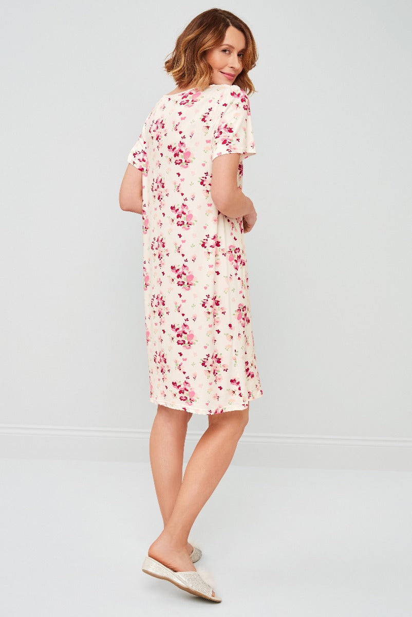 Lily Ella Collection model showcasing cream floral print shift dress with short sleeves and round neckline, paired with beige slip-on shoes.