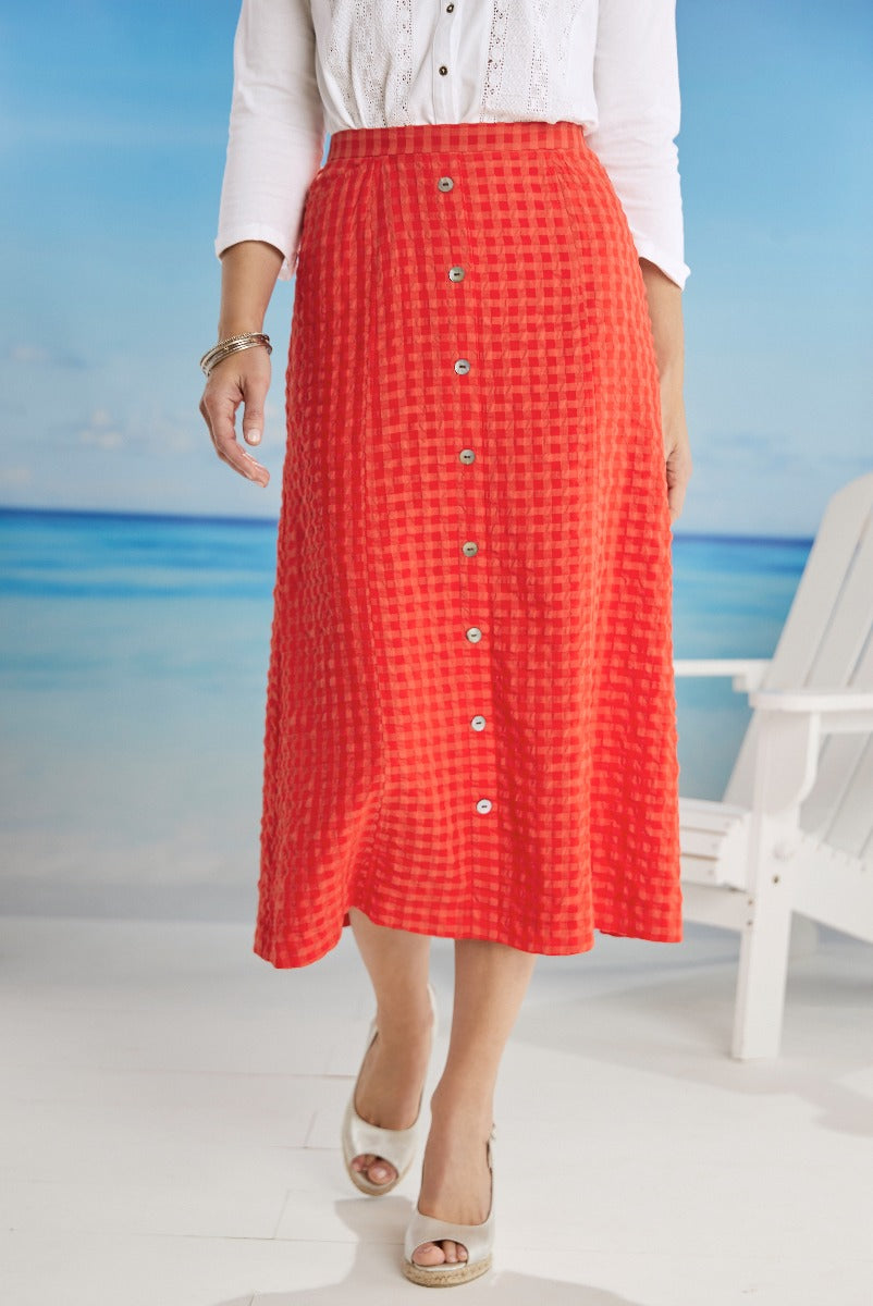 Lily Ella Collection vibrant coral red checkered midi skirt with front button detail, paired with white embroidered blouse and tan wedge sandals, casual elegant women's fashion.