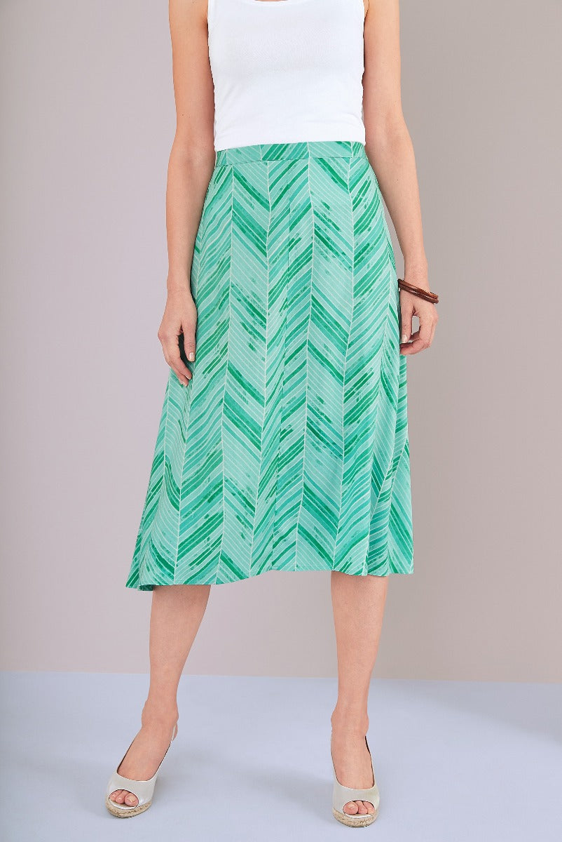 Lily Ella Collection green leaf print pleated midi skirt paired with white top and beige heels for a stylish summer outfit.