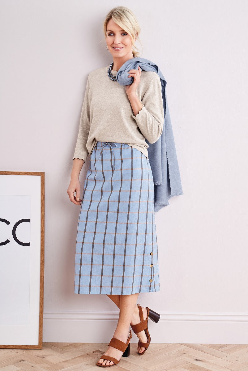 Lily Ella Collection stylish beige sweater with blue striped midi skirt and draped blue scarf, accessorized with chunky necklace and brown open-toe heels.