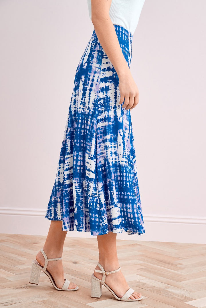 Lily Ella Collection blue and white tie-dye midi skirt paired with stylish beige high heels on wooden flooring.