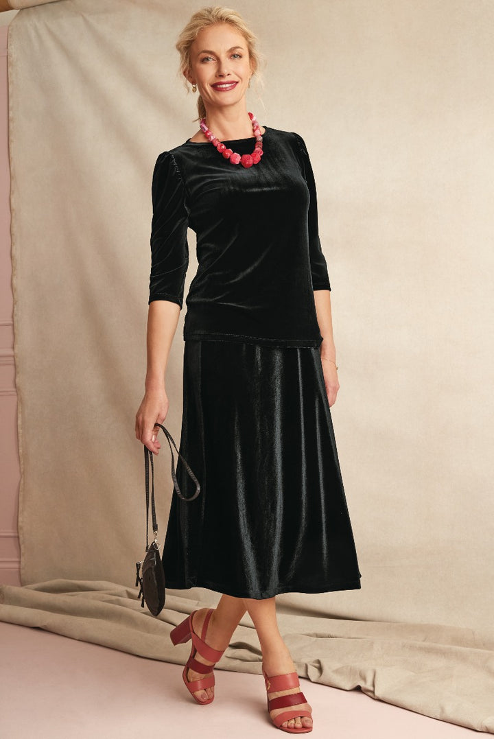 Lily Ella Collection elegant black velvet skirt and top, stylish women's clothing, chic 3/4 sleeve top, flowing mid-length skirt, paired with red sandals and statement necklace, classic fashion ensemble