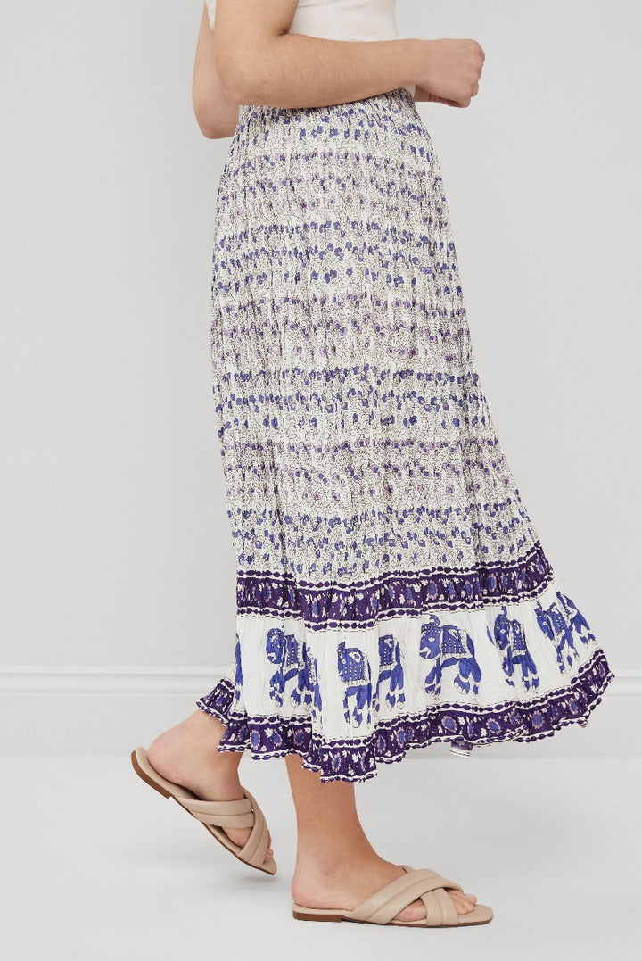 Lily Ella Collection blue and white patterned tiered maxi skirt with ruffle hem detail, stylish summer women's fashion skirt, elegant floral and elephant print design, paired with white top and beige sandals