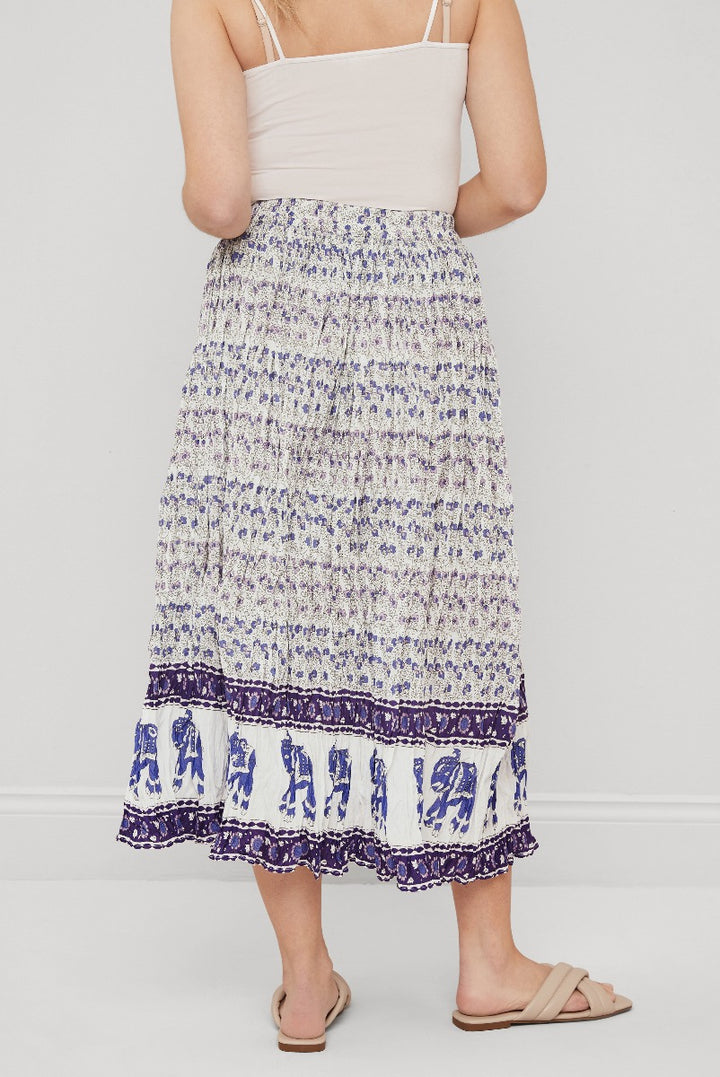 Lily Ella Collection mid-length skirt in purple and white pattern with ruffle hem detail, styled with a light beige camisole top and beige sandals, elegant summer outfit for women.