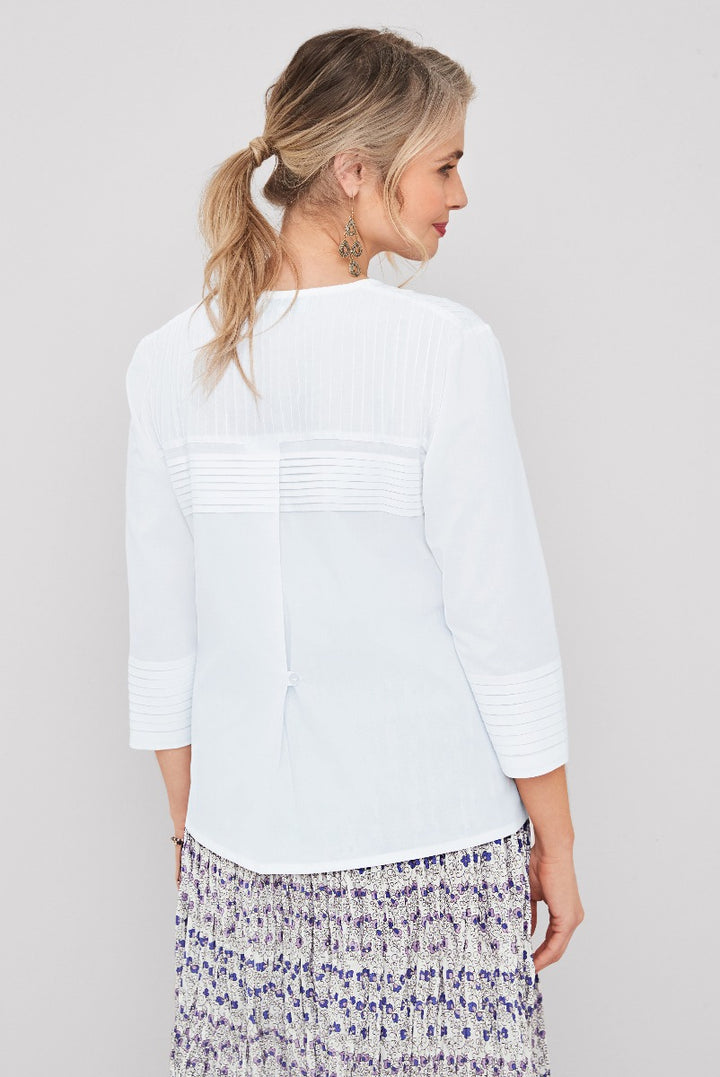 Lily Ella Collection elegant white pintuck blouse for women, featuring back details and styled with purple floral skirt.