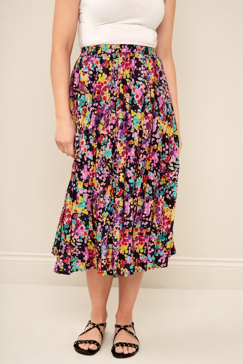 Lily Ella Collection colorful floral print midi skirt in black with vibrant multicolor pattern, paired with white top and black strappy sandals, chic women's spring/summer fashion.